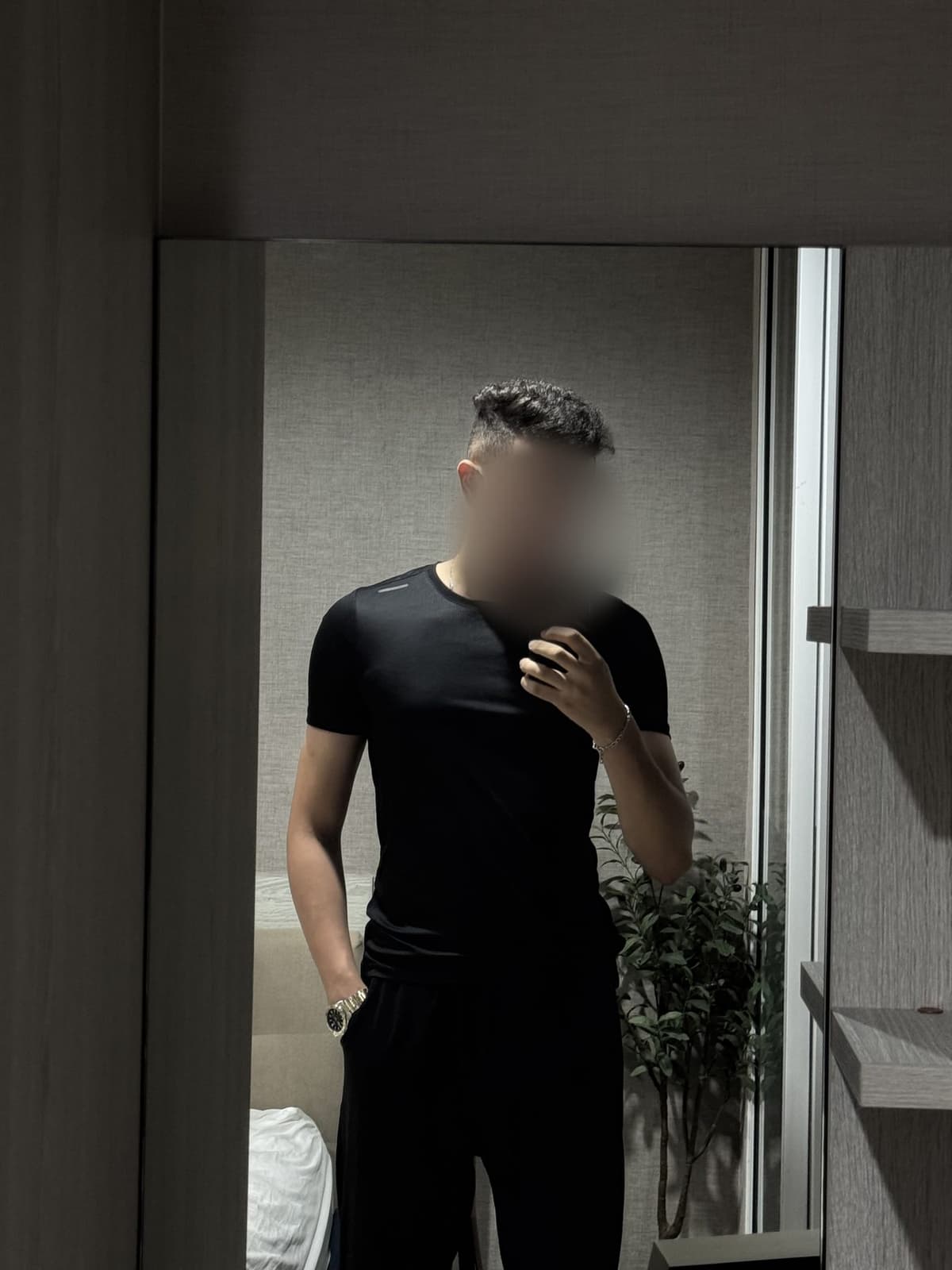 Mehdi in a fitted black t-shirt next to a plant